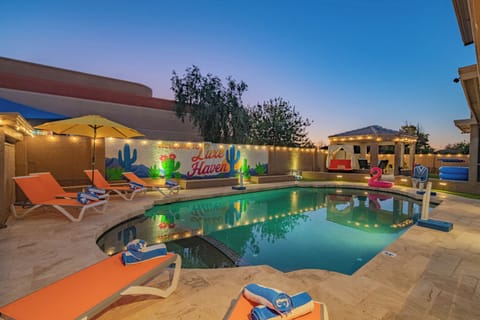 Resort-style pool with lounge chairs, umbrellas, and colorful desert mural