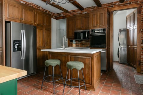 Kitchen with exposed brick and wood beams, electric range, and moveable island.