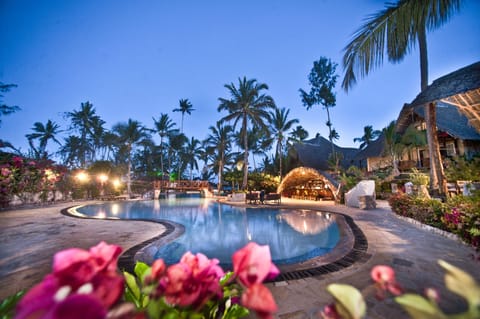 Sip cocktails as evening lights shimmer across the calm pool.