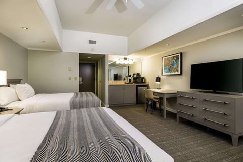 Queen bed room with workspace, TV, and mini kitchen area