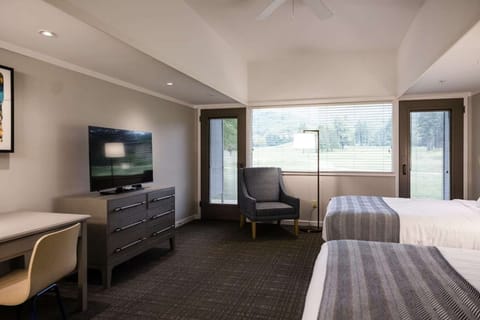 Room with TV, dresser, and two beds facing large windows