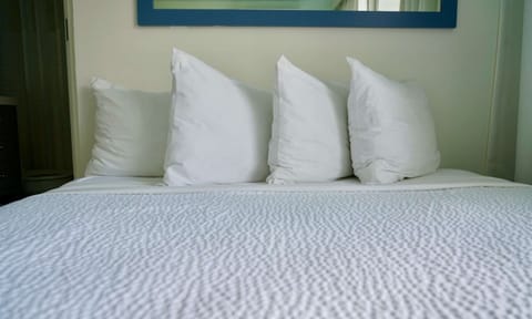 White bed with four pillows against a clean headboard