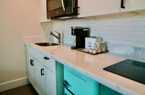 Clean kitchen counter with sink, coffee maker, and small stove top