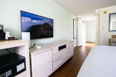 Room with wall-mounted TV, wood floors, and a long storage cabinet