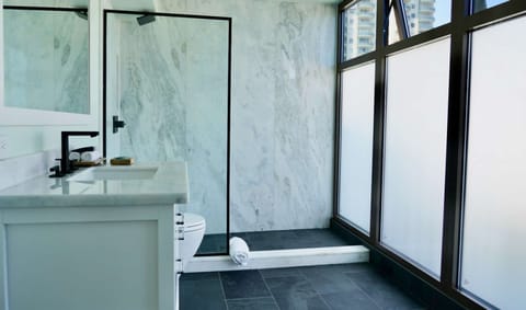 Bathroom with marble shower and tall frosted windows