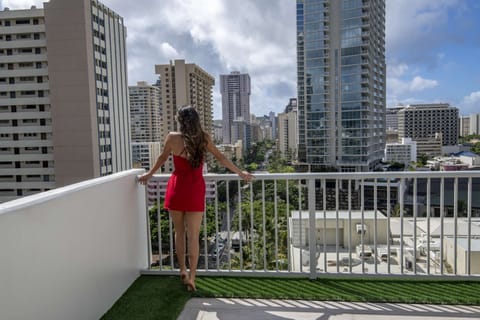 Guest standing on balcony with tall city buildings around her