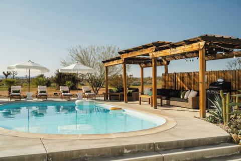 Sunlit desert pool oasis—loungers, shade, and expansive skies made for relaxation.
