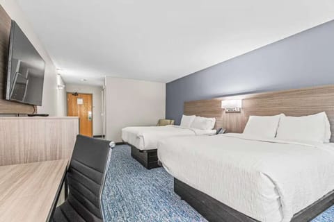 Room with two comfy beds, desk, TV, and soft blue carpet