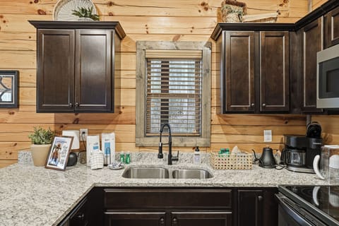 Your fully equipped kitchen features granite counters, dark wood cabinets, and modern appliances for preparing memorable meals together.