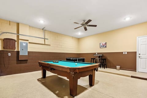 Step into this spacious game room featuring a classic pool table framed by warm brown walls and soft beige tones. The ceiling fan adds a touch of comfort, making it an ideal spot for relaxation and friendly competition.