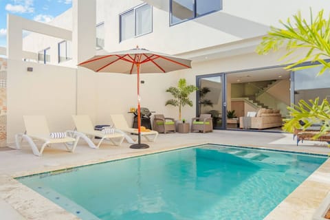 Private pool retreat with loungers, shaded umbrella, and outdoor grill.
