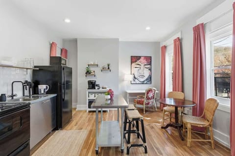 Fully equipped kitchen with dining table and coffee station, plus sunny window-side seating.