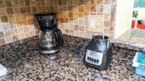 Start your day with fresh coffee from the Toastmaster coffee maker or whip up smoothies with the Oster blender base, all set on beautiful granite countertops with a stylish tiled backsplash for a warm and functional kitchen corner.