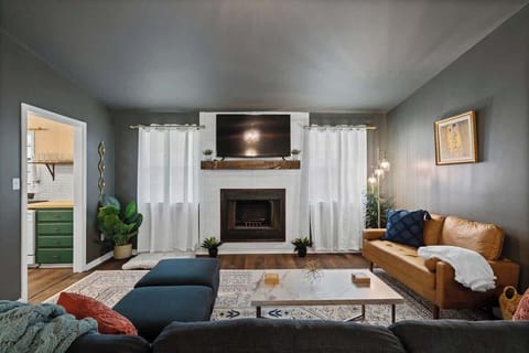 Bright living room w/ cozy seating, fireplace & large windows filling the space w/ natural light