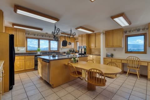 Spacious kitchen with tile flooring, light wood cabinetry, a central island, and a dining area.