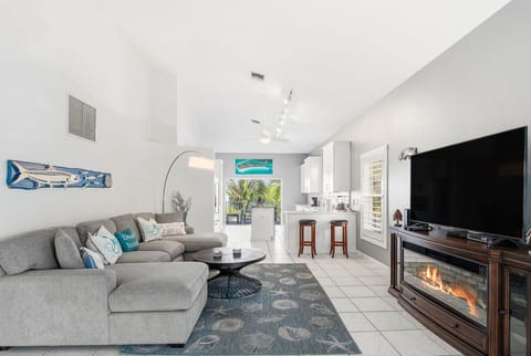 Relax in your bright, open-concept living space with comfortable sectional seating, modern kitchen, and cozy fireplace for the perfect vacation atmosphere.