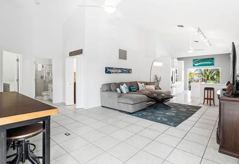 Relax in your spacious living area featuring a plush sectional sofa, modern coffee table, and stylish coastal decor with glimpses of the tropical outdoors.