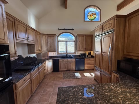 Chef's kitchen fully equipped with double oven, dishwasher, gas stove, and large refrigerator. 