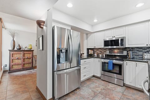 Fully equipped kitchen with stainless steel appliances, bar seating for three, and a convenient laundry area with a washer and dryer.