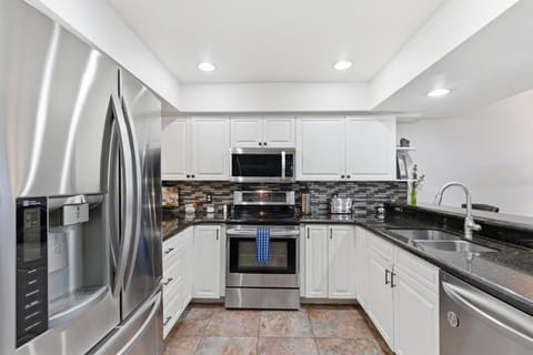 Fully equipped kitchen with stainless steel appliances, bar seating for three, and a convenient laundry area with a washer and dryer.