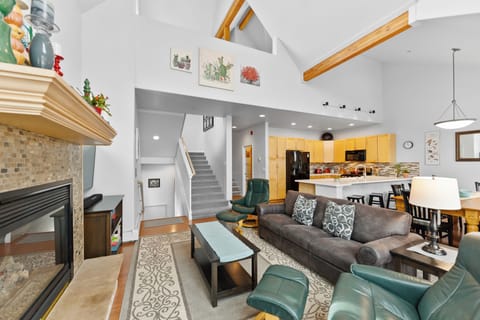 Living room with vaulted ceilings, TV, and cozy fireplace.