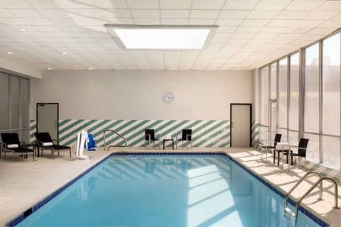 Indoor pool with lounge chairs and natural light from windows