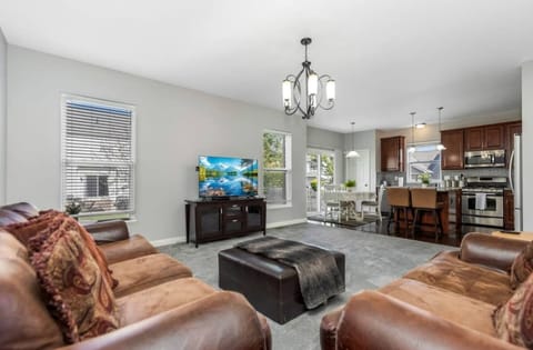 Bright living room w/ plush seating, TV, & open flow into the kitchen for easy group hangouts.