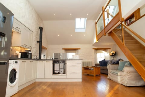 Modern open-plan kitchen and lounge with wooden stairs, skylight windows, and hardwood flooring