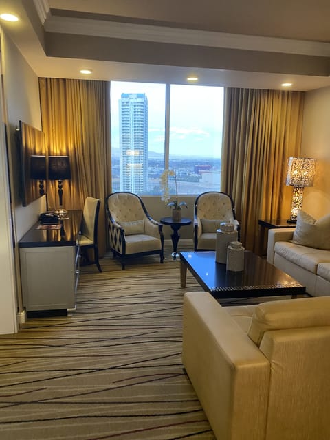 Spacious living room with seating and large windows overlooking Las Vegas.