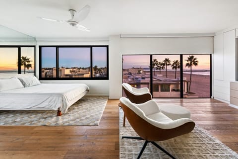 Bright primary bedroom with ocean views, featuring a comfortable king bed and floor-to-ceiling windows.