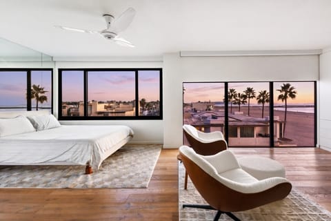 Bright primary bedroom with ocean views, featuring a comfortable king bed and floor-to-ceiling windows.