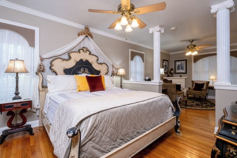 The Majestic Spa Suite bedroom with an ornate king bed and stately architectural columns.