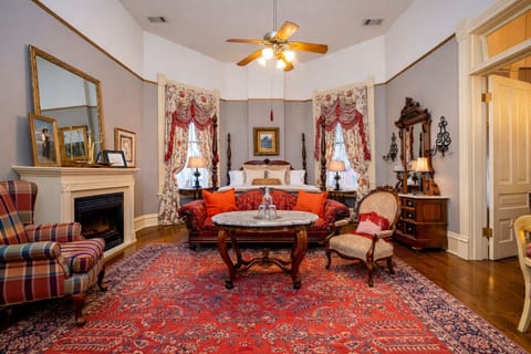 Victorian seating area with decorative fireplace, antique tables, and tall windows.  Washburn-Welch room at The Empress of Little Rock.