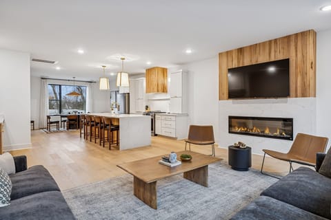 Living Room: Experience sophisticated living. From the sleek fireplace feature to the inviting sofa and fully-equipped kitchen, every detail in this space is curated for your ultimate comfort and enjoyment.