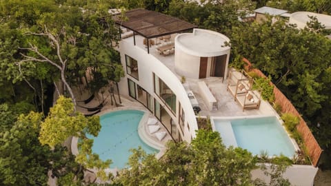 An aerial view of Villa Lanay, with curved architecture, lush jungle, and a private pool below.