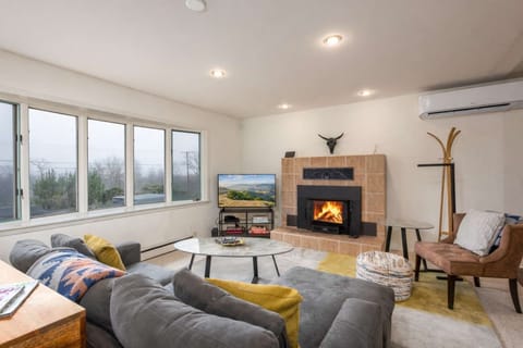 Relax in this sunlit living room with cozy seating, fireplace, and valley views—perfect for unwinding, movie nights, or gathering after a day out.

