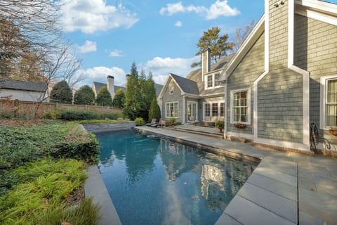 Sparkling backyard pool beside a charming stone home, perfect for sunny afternoons outdoors