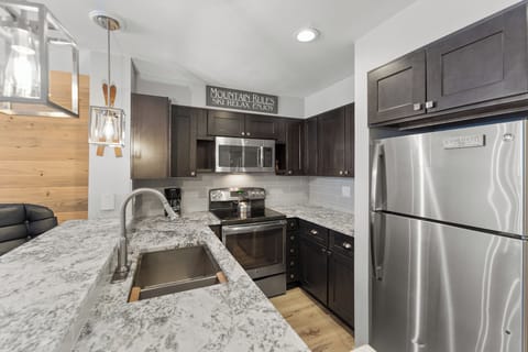 Full kitchen with stainless steel appliances and breakfast bar.