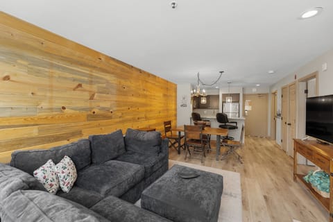 The living area features a stone surround fireplace, TV, and queen sleeper sofa with lake and mountain views.