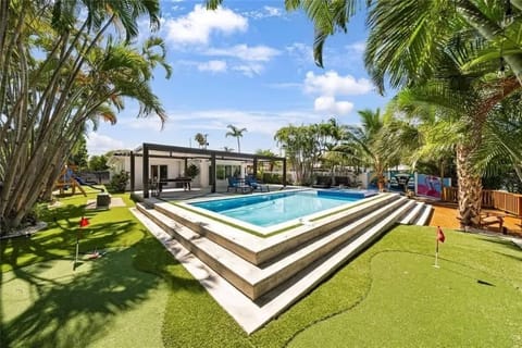 Elevate your leisure time in this luxurious backyard escape—complete with a raised pool, putting green, and shaded lounge area. Ideal for vacation rental guests who crave relaxation, recreation, and resort-style vibes. Your private paradise awaits!
