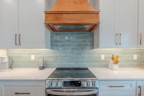 Prepare culinary delights in your stunning modern kitchen featuring gleaming countertops, designer tile backsplash, and premium stainless steel appliances.