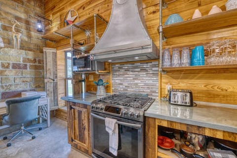 A chef-ready kitchen featuring a gas range, open shelving, and handcrafted details throughout