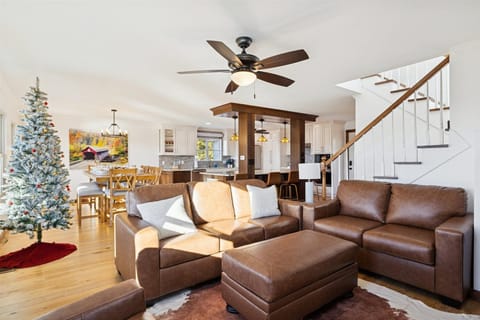 Spacious area with modern decor, a festive tree, and open kitchen views for family fun!