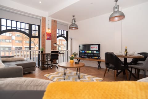 A bright, airy living room with stunning double-window views, two dining tables, a sofa and sofa bed, 4K TV, workspace and soft furnishings, offering a comfortable stay in the heart of Birmingham city centre.