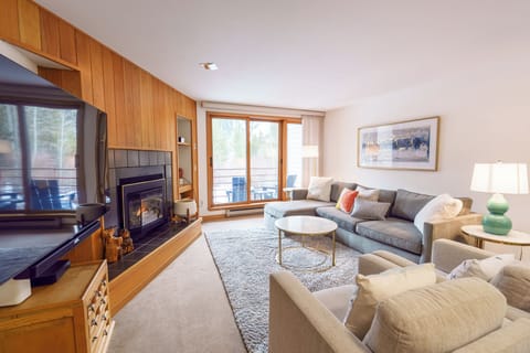 Unwind in your cozy living room with plush seating, crackling fireplace, and balcony views of nature's beauty.