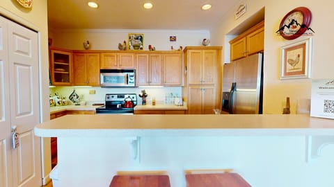 Your fully equipped kitchen awaits with warm wood cabinets, stainless appliances, and a breakfast bar perfect for morning coffee.