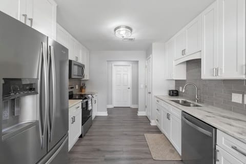 Cook up your favorite meals in this fully equipped, sleek kitchen featuring stainless steel appliances, white shaker cabinets, and a stylish backsplash.