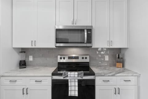 This modern kitchen features gleaming white cabinetry, sleek stainless steel appliances, and a timeless subway tile backsplash that ties it all together.