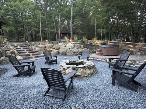 Custom firepit surrounded by Adirondack chairs woodburning hot tub & bench swing