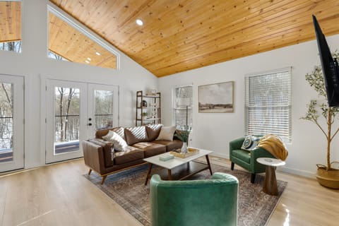 Bask in natural light and pond views from this stylish open-concept living area—featuring a fully equipped kitchen, cozy seating, and direct access to the outdoor deck.